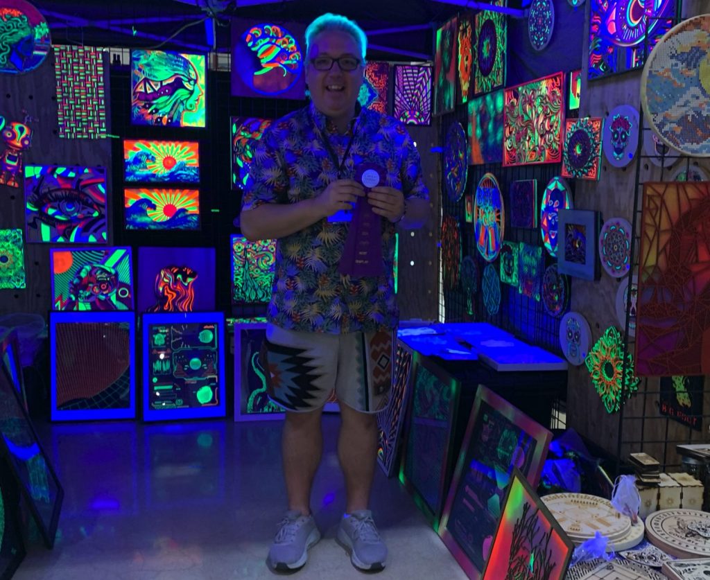 Artist Michael Lawson with blacklight wood artworks.