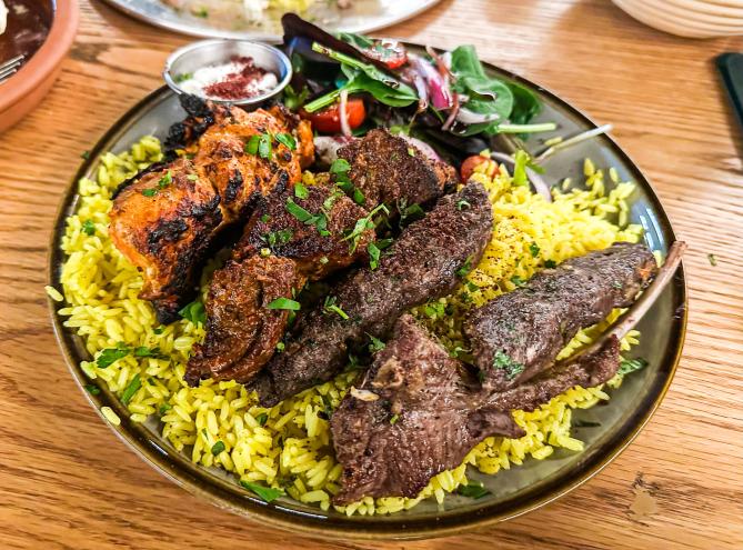 A bowl of rice topped with lamb and beef skewers from Ayat.