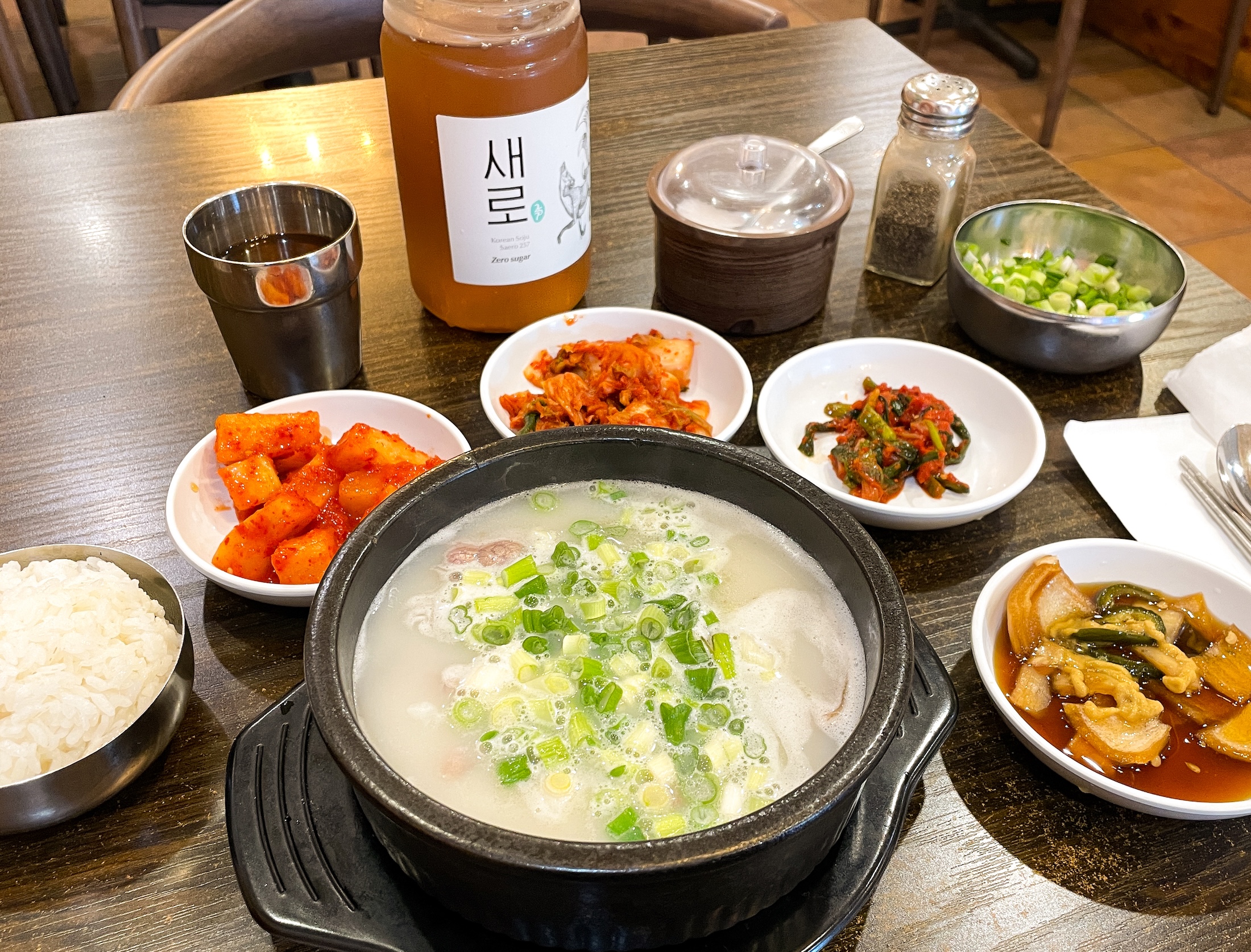 Doma Seolleongtang soup and all the sides sitting on a brown table.