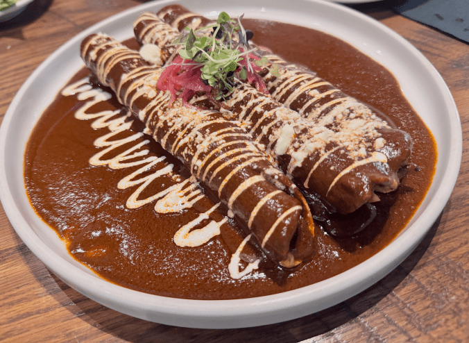 Close up of Milagro tacos cantina chicken taquitos in a mole sauce