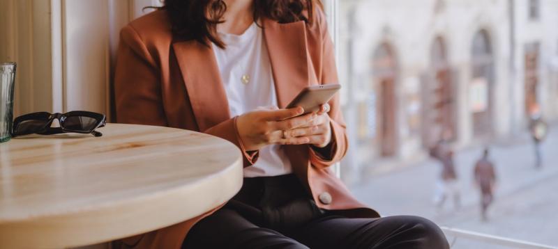 Woman sitting in cafe texting on the phone to illustrate a story about how Texans are less likely to face ghosting from potential romantic partners.
