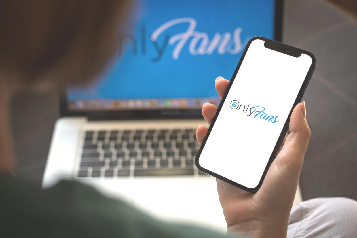 Person holding phone with OnlyFans logo shown on screen