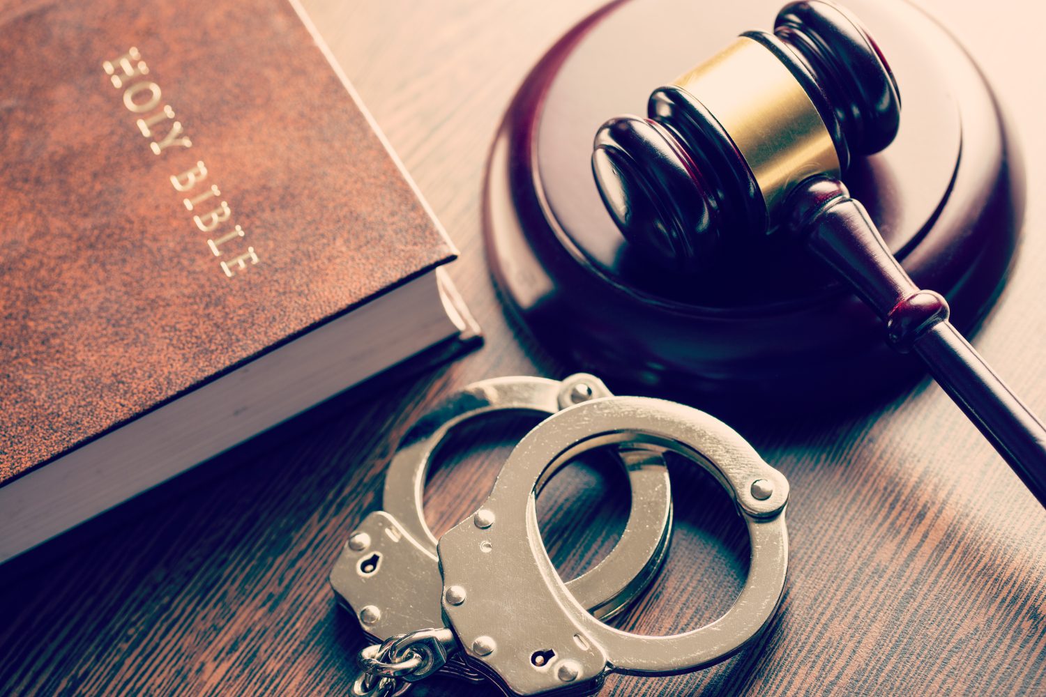 a bible with a judge's gavel and handcuffs