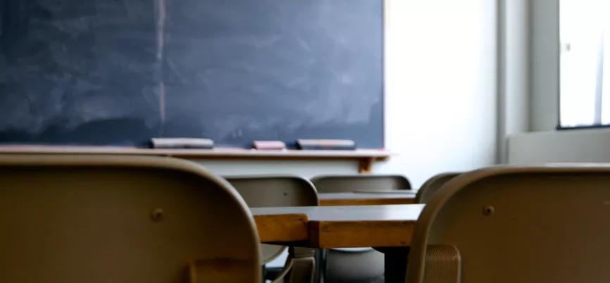 empty school classroom with chairs, desks and blackboard