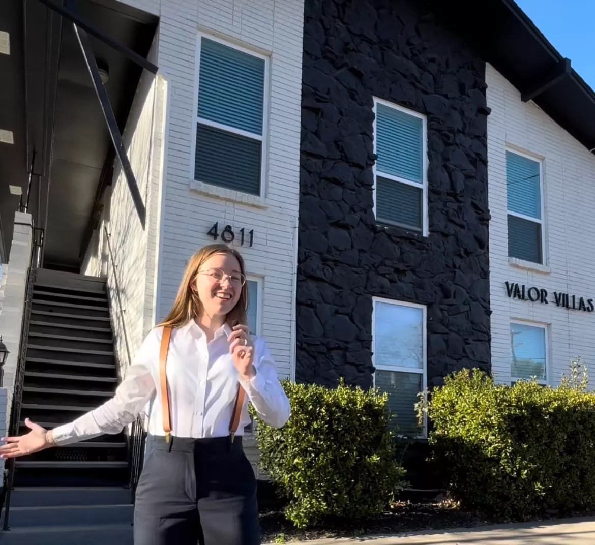 Dallas realtor Sara Williams stands in front of a white house. She's going viral on TikTok for her fun renatl videos,