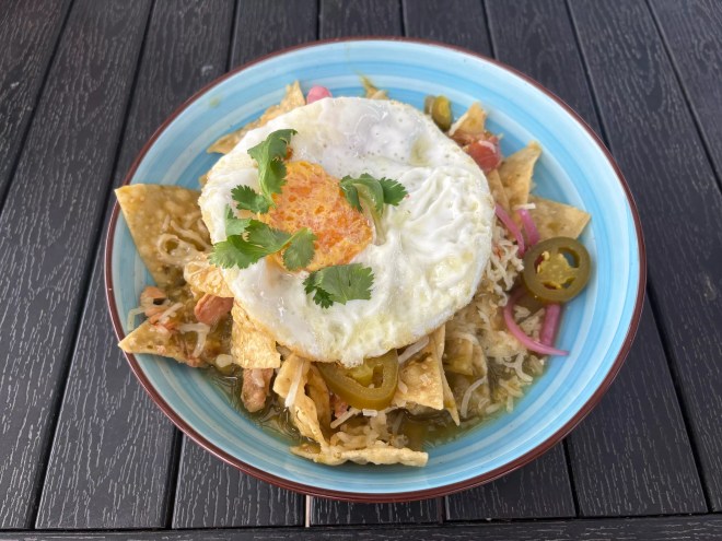 chilaquilas in a bowl setting on a wooden table.