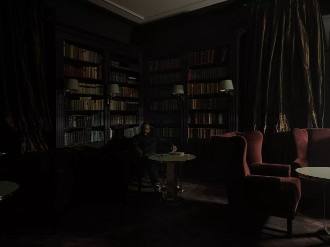 Man sitting in the dark in front of bookshelves